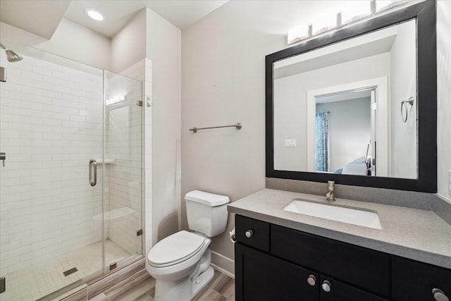 bathroom with ensuite bathroom, toilet, wood finished floors, vanity, and a stall shower