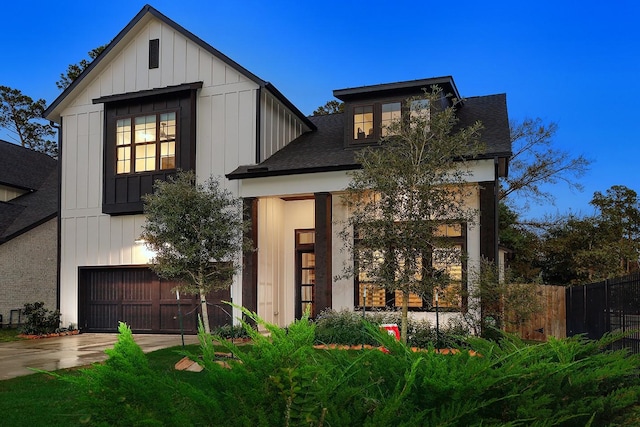 modern farmhouse featuring a garage, fence, board and batten siding, and concrete driveway