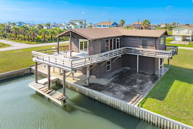 back of house with a yard, a shingled roof, a deck with water view, and driveway