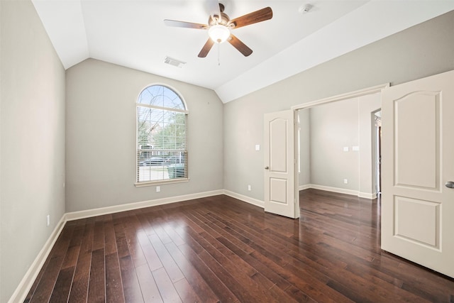 empty room featuring vaulted ceiling, dark wood finished floors, visible vents, and baseboards