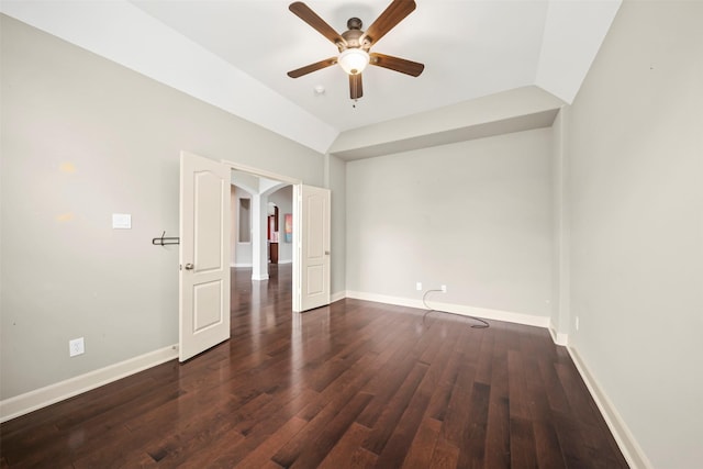 empty room featuring lofted ceiling, ceiling fan, baseboards, and dark wood-style flooring