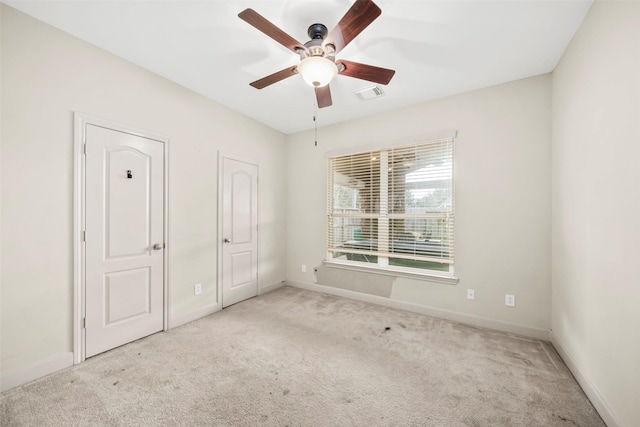 empty room featuring baseboards, visible vents, and light colored carpet