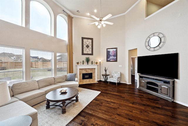 living area featuring baseboards, ornamental molding, dark wood finished floors, and a tiled fireplace