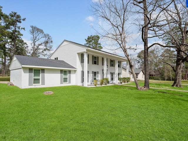 greek revival house with brick siding, roof with shingles, and a front yard