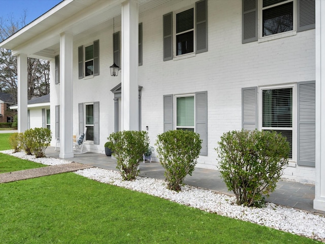 view of front facade with brick siding, a porch, and a front yard