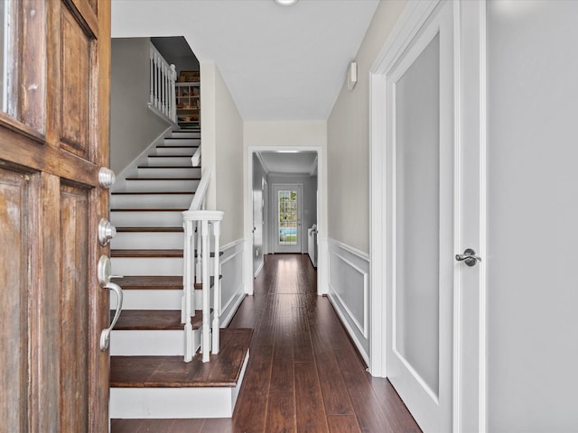 entrance foyer featuring hardwood / wood-style floors, a decorative wall, stairs, and wainscoting