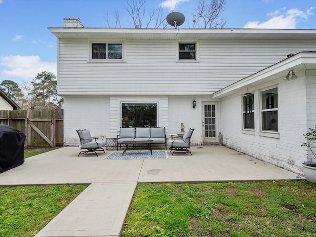 rear view of property featuring a patio, fence, a chimney, outdoor lounge area, and brick siding