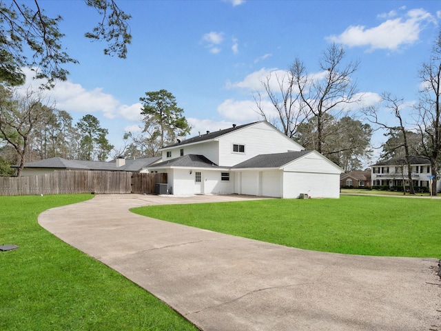 back of house featuring a lawn, driveway, a garage, and fence