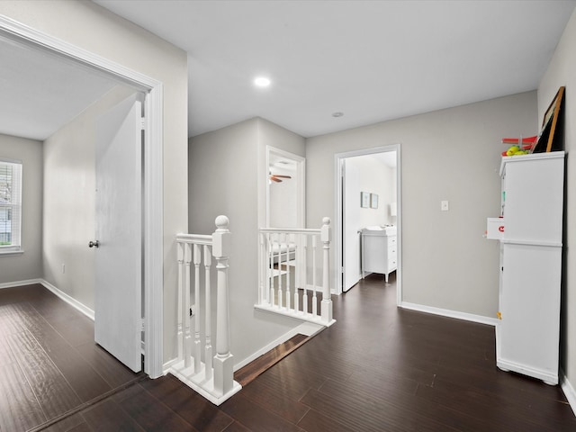 corridor with an upstairs landing, recessed lighting, baseboards, and wood finished floors