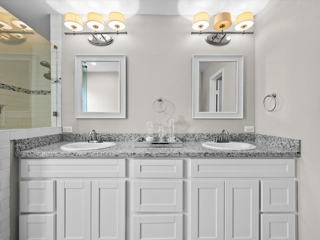 full bathroom with a tile shower, double vanity, and a sink