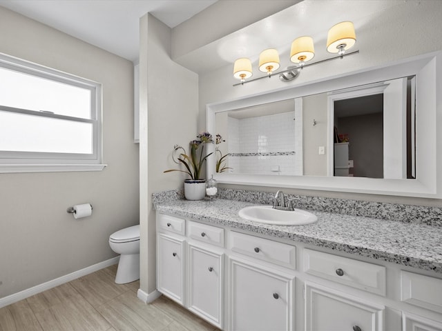 bathroom with vanity, toilet, and baseboards