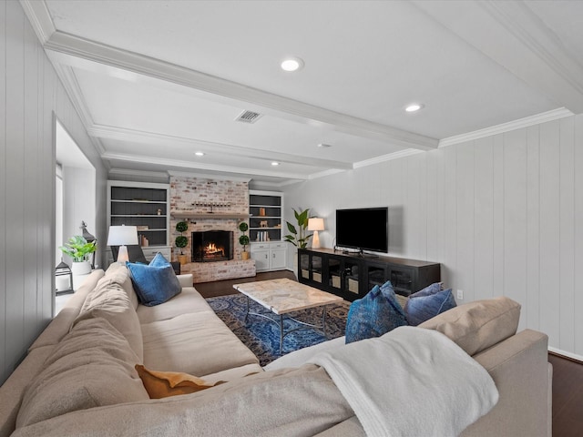 living area with visible vents, a brick fireplace, beamed ceiling, ornamental molding, and wood finished floors