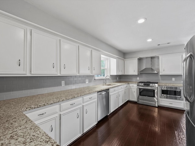 551 Hermitage Ct, Conroe, TX 77302 - kitchen featuring stainless steel appliances, wall chimney range hood, white cabinets, a sink, and dark wood-style flooring