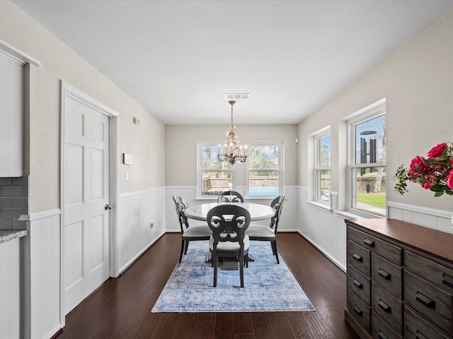 dining room featuring dark wood finished floors, a wainscoted wall, a chandelier, and visible vents