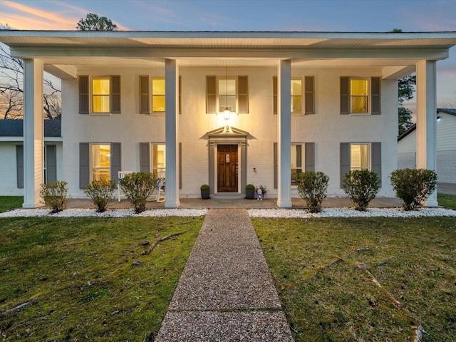 view of front of property featuring brick siding, a porch, and a front lawn