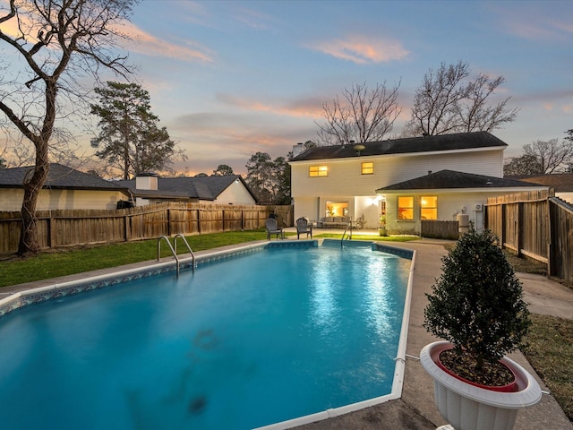 pool at dusk featuring a patio area, a fenced in pool, a lawn, and a fenced backyard