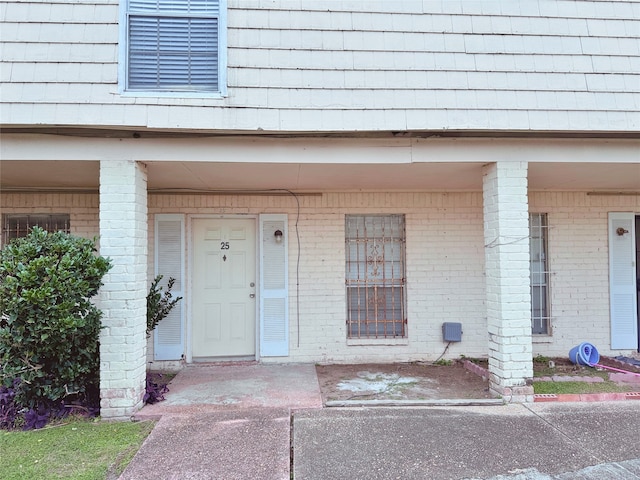 view of exterior entry with brick siding and mansard roof