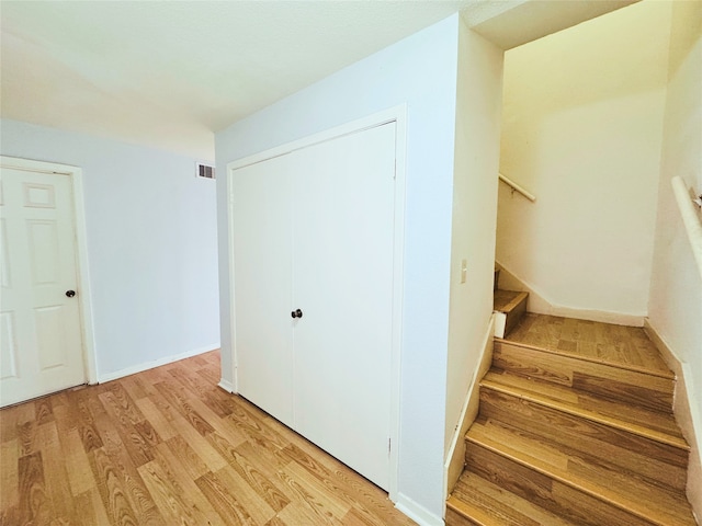 staircase featuring wood finished floors, visible vents, and baseboards