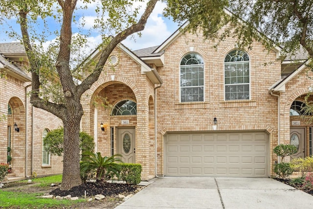 view of front facade with a garage, brick siding, and driveway