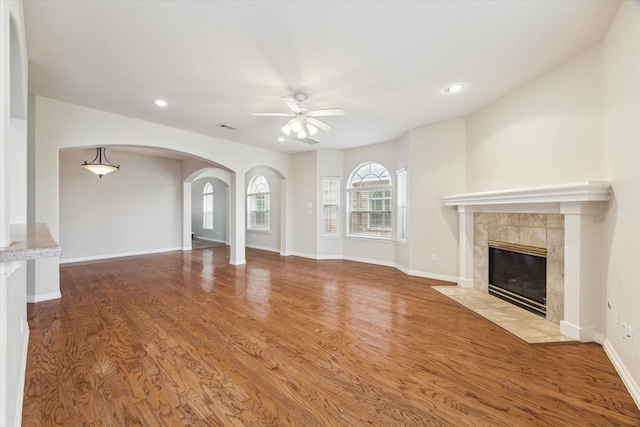 unfurnished living room with baseboards, visible vents, ceiling fan, wood finished floors, and a fireplace