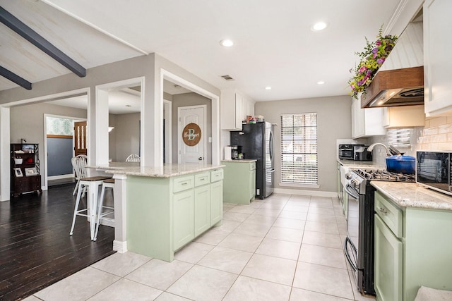 kitchen with light stone countertops, stainless steel appliances, baseboards, decorative backsplash, and green cabinetry