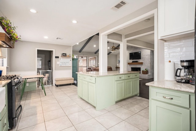 kitchen with green cabinets, light tile patterned floors, a fireplace, and range with gas stovetop