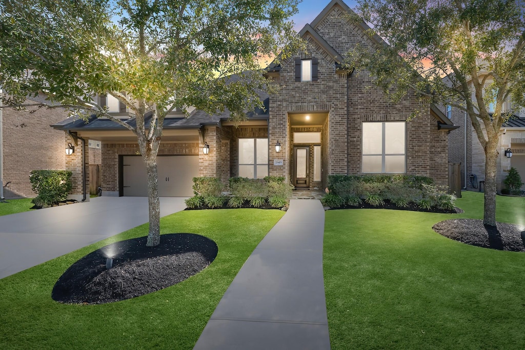 view of front of house featuring a garage, concrete driveway, brick siding, and a front lawn