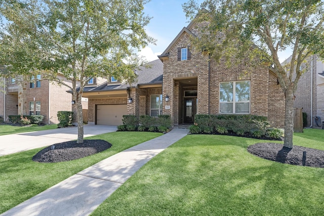 traditional-style house featuring a shingled roof, a front yard, concrete driveway, and brick siding