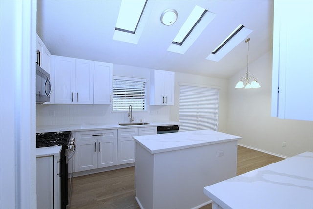 kitchen featuring white cabinetry, appliances with stainless steel finishes, a sink, and decorative light fixtures