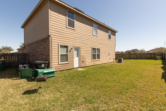 back of house with a yard, brick siding, central AC, and a fenced backyard