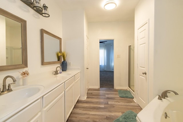 full bath featuring a garden tub, wood finished floors, double vanity, and a sink