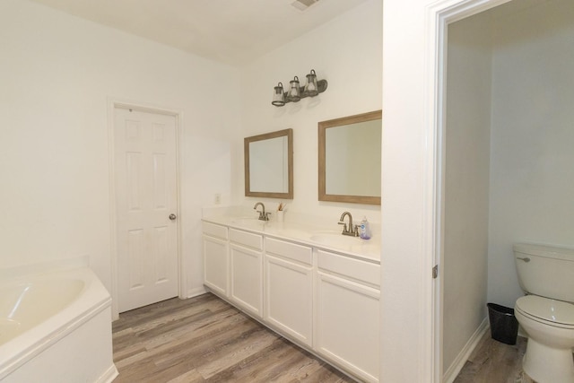 full bathroom featuring double vanity, wood finished floors, toilet, and a sink