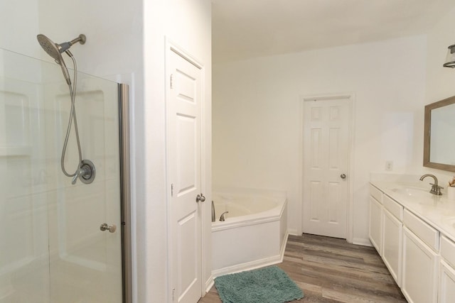 full bath with vanity, a garden tub, wood finished floors, and a stall shower