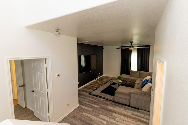 living room featuring a textured ceiling, baseboards, and wood finished floors