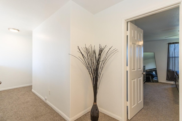 hall featuring carpet flooring and baseboards