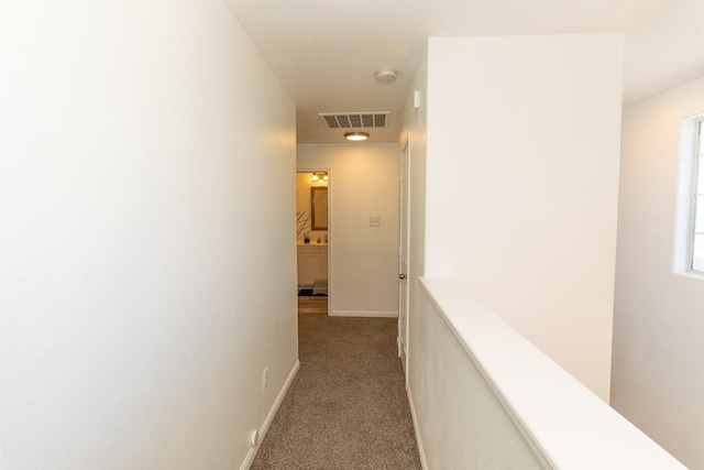 corridor featuring visible vents, baseboards, and carpet floors