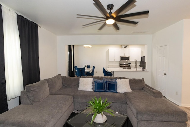 living room with visible vents, wood finished floors, and ceiling fan