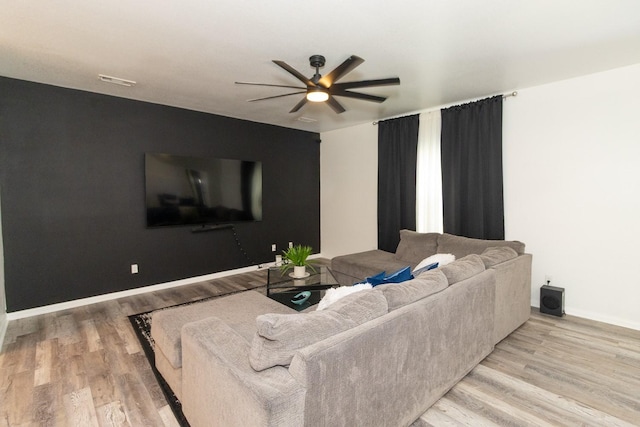 living area featuring baseboards, a ceiling fan, and wood finished floors