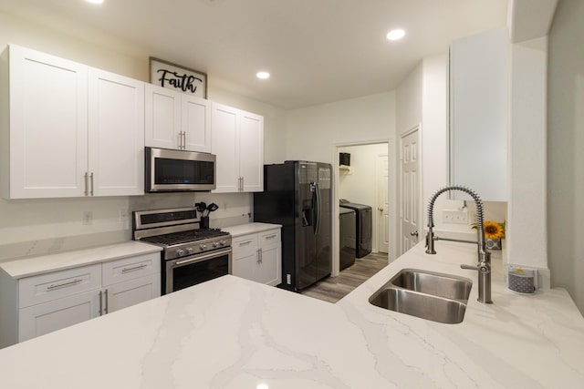 kitchen with recessed lighting, separate washer and dryer, white cabinets, stainless steel appliances, and a sink