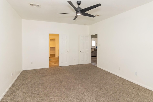 unfurnished bedroom featuring a walk in closet, carpet flooring, baseboards, and visible vents