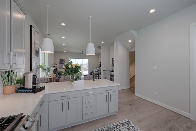 kitchen with a peninsula, light wood-type flooring, light countertops, and recessed lighting