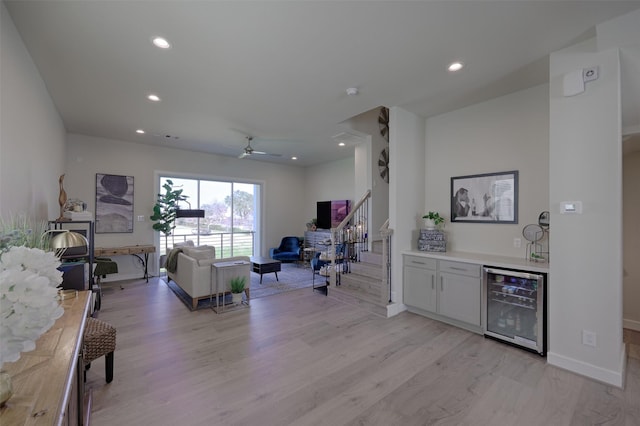 living room featuring light wood finished floors, beverage cooler, stairs, a bar, and recessed lighting