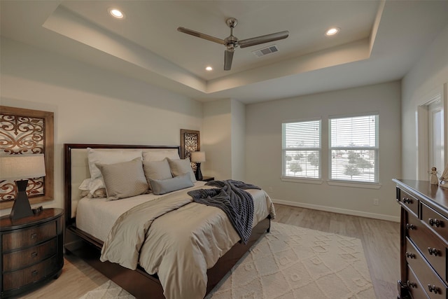 bedroom featuring visible vents, a raised ceiling, baseboards, light wood-style flooring, and recessed lighting