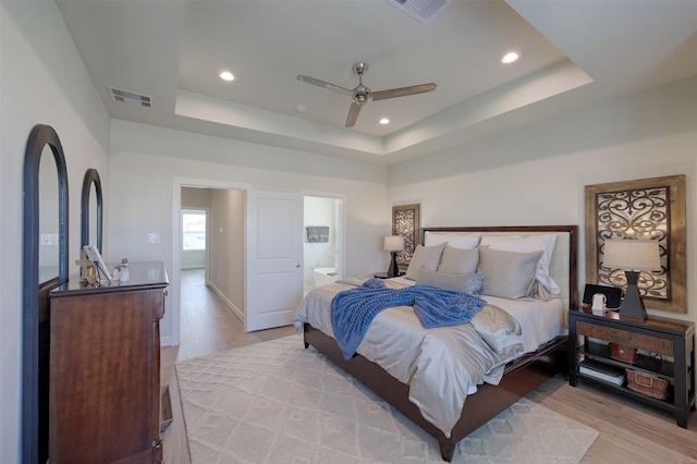 bedroom with recessed lighting, a raised ceiling, visible vents, and light wood-style flooring