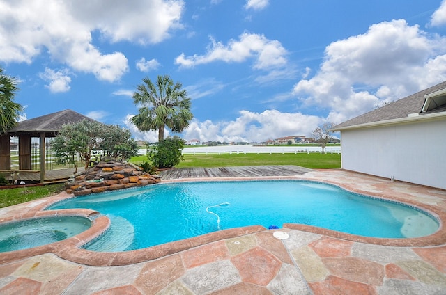 view of pool featuring a pool with connected hot tub and fence