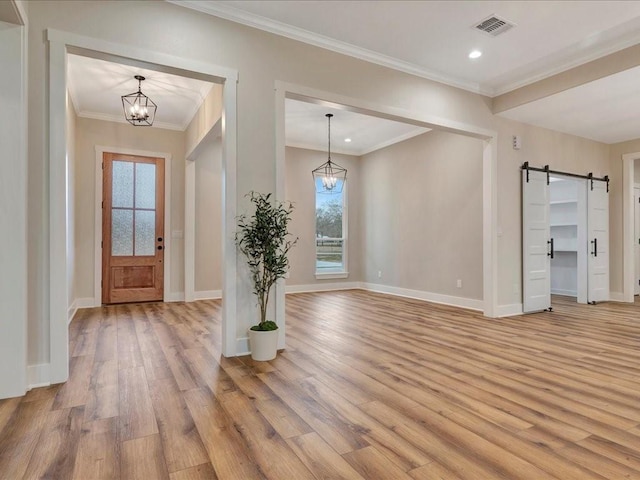 foyer with light wood-type flooring, a barn door, plenty of natural light, and an inviting chandelier