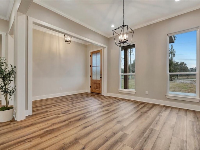 unfurnished dining area with light wood finished floors, baseboards, crown molding, and an inviting chandelier