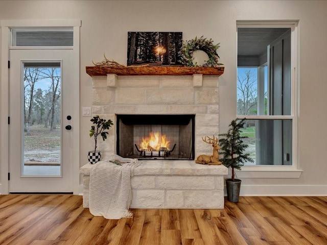 living area featuring a fireplace, wood finished floors, and baseboards