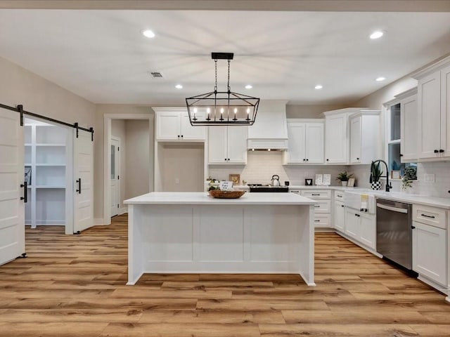 kitchen with a barn door, white cabinetry, light countertops, dishwasher, and decorative light fixtures