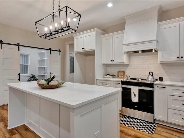 kitchen with stainless steel electric range oven, a barn door, and white cabinets